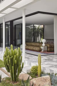 Modern living room with concrete floor, glass walls, and marble accents.