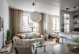 A minimalist apartment living room with neutral-toned decor and plants.