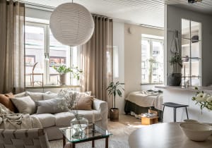 A cozy, minimalist apartment featuring neutral tones, soft textiles, and wooden accents.