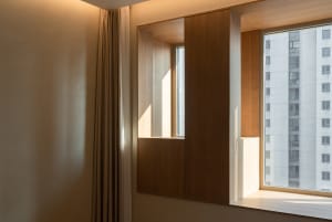 A modern residential space featuring a wooden pane wall and window with a view of an adjacent building.