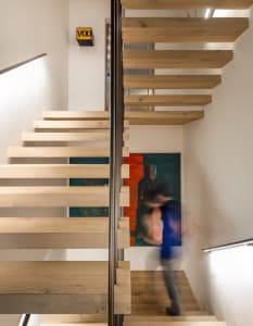 Modern interior with wooden staircase and abstract painting.