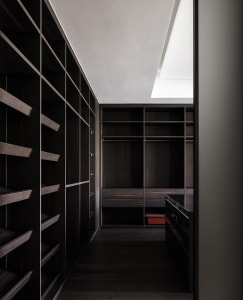 A minimalist dark wood closet with shelves, drawers, and skylights.