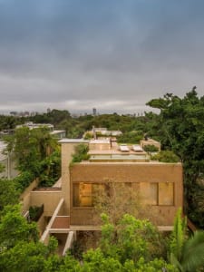 An elevated view of a modern house with a wooden exterior surrounded by lush greenery.