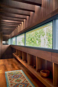 A modern interior with a wooden staircase, featuring a colorful patterned rug and built-in shelves with wooden bowls.