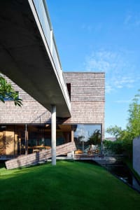 Modern residential architecture featuring wooden shingles, concrete, and glass elements.