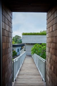 A wooden pathway with concrete railings and a green roof on a rooftop.