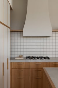 Modern kitchen with white tiled backsplash, wooden cabinetry, and a concrete countertop.
