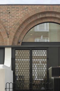 Modern building facade with brick walls, large glass panel, and metal railings.