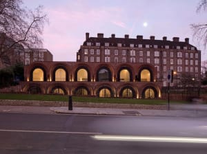 Modern residential building made of brick with large arched windows and a controlled parking zone sign.