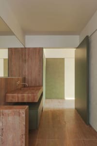 A minimalist bathroom with concrete walls and floor, featuring a rectangular sink with a metallic faucet and a large mirror a