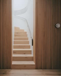 A minimalist staircase with wood steps and a metal railing.