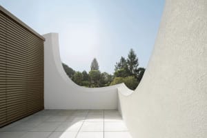 An architecturally minimalist balcony featuring concrete walls and a curved design.