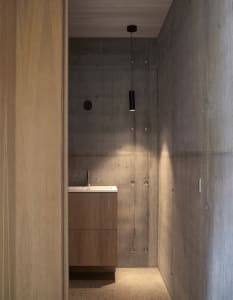 A minimalist bathroom with concrete walls and wooden vanity.