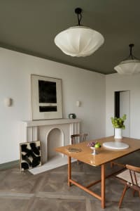 A minimalist dining room with wooden table, stone fireplace, and abstract art.