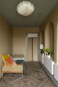 A modern living room with floor tile, featuring a comfortable seating area, a side table, and a decorative console with green
