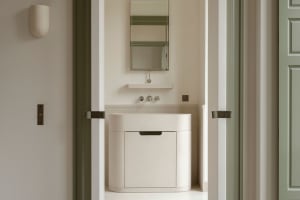 A minimalist bathroom featuring white stone sink, white walls, and a green door.