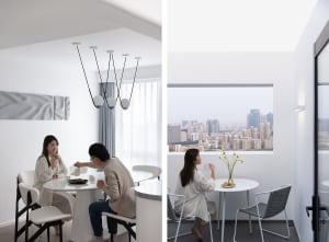 Two people sitting at a round dining table with white chairs and minimalist decor.