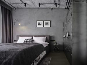 A bedroom with industrial design features, showcasing concrete walls and a large bed.