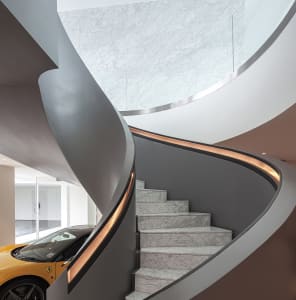 A modern residential staircase with marble steps and a sleek, curved design.