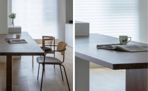 Modern minimalist dining room featuring a long wooden dining table with a concrete countertop, minimalistic furniture, and a 