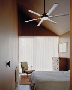 A minimalist bedroom with a white flat door, sheer white curtains, and a large window, featuring a bed with a white bedspread