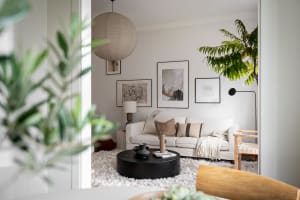 A minimalist living room with a white couch, round black coffee table, and framed artwork on the wall.