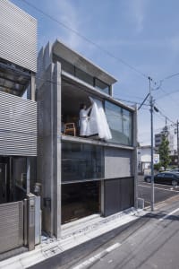 A modern, minimalist house exterior with a concrete facade and large windows.