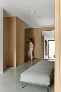 A modern residential interior featuring wooden walls, concrete flooring, and metal accents.