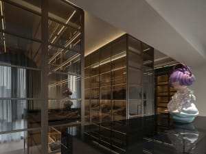 A stylish glass-walled closet with an artistic statue standing on a pedestal within it.