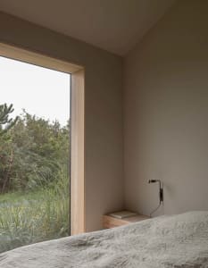 A minimalist bedroom with natural wood accents and grey fabric bedding