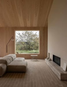 Modern minimalist residential interior featuring wood accents and a large window with a view of greenery.