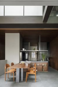 A modern living room with concrete walls, a wooden dining table, and a minimalist design.