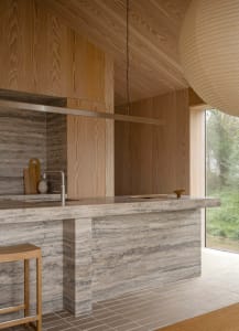 Modern kitchen with marble countertops and wooden stools.