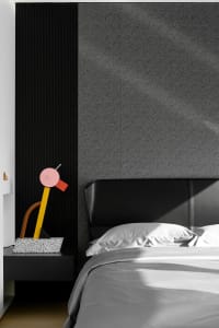 Modern minimalist bedroom featuring a black upholstered headboard and gray bedding.