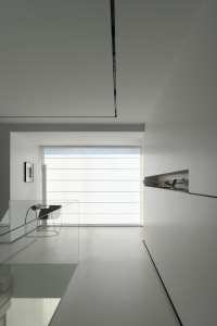 A minimalist white interior space with glass elements and a large window.