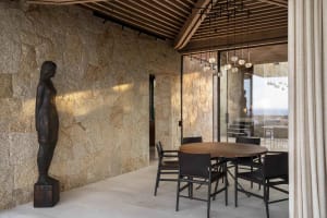 Modern dining room featuring a stone wall and wood dining table.