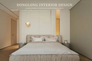 A minimalist bedroom with white walls, a beige upholstered bed, and a round gold moon art piece on the wall.