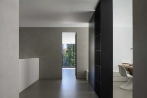 Modern minimalist hallway with concrete walls and floor, large window, and simple design elements.
