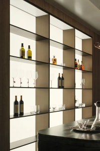 Modern minimalist bar with illuminated glass shelving displaying bottles and glasses.