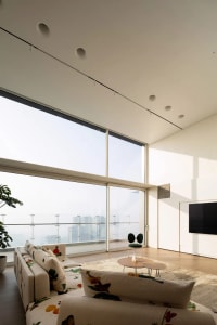 A contemporary living room featuring a sectional sofa with floral upholstery, a low coffee table, and floor-to-ceiling window