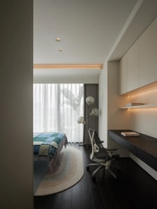 Modern minimalist bedroom with neutral tones, featuring a bed covered in blue and green checkered bedding and a sleek, ergono