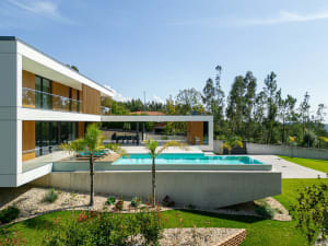 A modern residential building with concrete walls and a glass pool area.