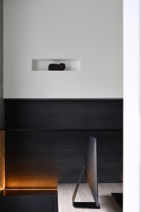 A modern office space featuring a wooden desk and a black computer monitor.