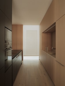 Modern minimalist kitchen with hardwood floors and wooden cabinetry.