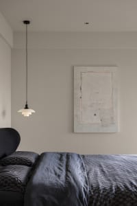 Minimalist bedroom featuring dark bedding with a patterned textile design.