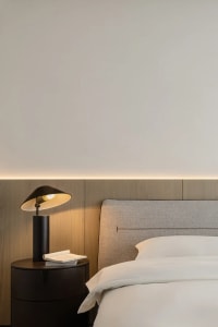A minimalist bedroom featuring a grey upholstered headboard and white bedding.