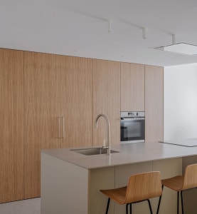 Modern minimalist kitchen with wooden cabinets and stainless steel appliances.
