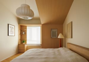 A modern minimalist bedroom featuring a bed with white fabric bedding and wooden headboard, along with a wooden floor and cei