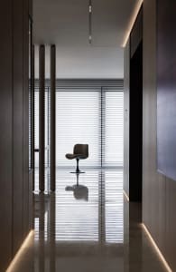 A minimalist office with a glass window and a single chair reflected in the glossy floor.