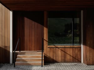 A modern front entryway featuring wooden steps and walls with a large window.